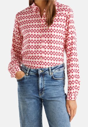 Button-up shirt in a pink and red diamond pattern, made of lightweight fabric. Paired with mid-rise blue denim jeans. Long sleeves and classic collar.