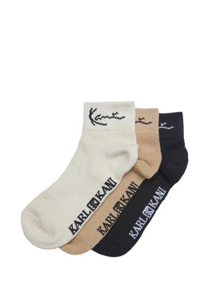 Tres pares de calcetines tobilleros en blanco, beige y negro, cada uno con el texto y el logo "KARL LAGERFELD" cerca del puño y del pie.