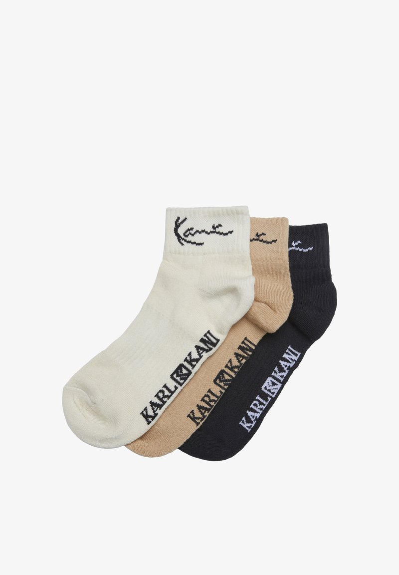 Tre paia di calzini alla caviglia nei colori bianco, beige e nero, ciascuno con la scritta "KARL LAGERFELD" e il logo vicino al bordo e alla pianta del piede.