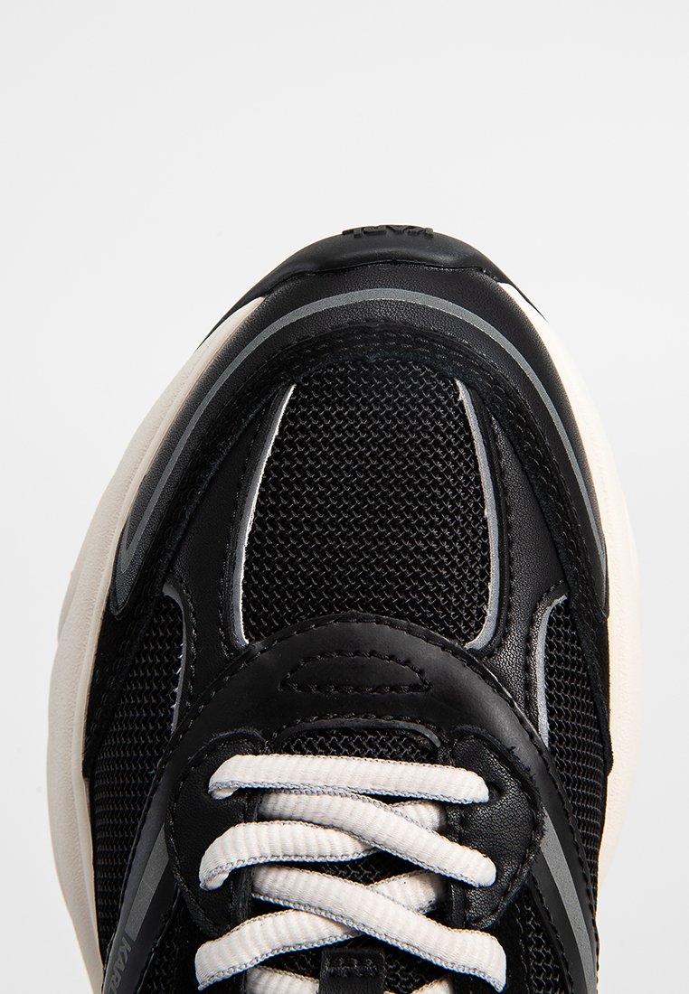 Sneaker noir avec tige en maille, accents en synthétique, lacets blancs, détails cousus, col rembourré et semelle intercalaire de couleur crème.