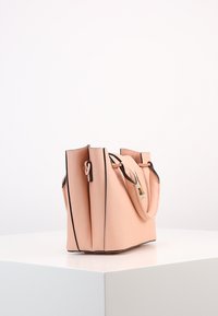 Strukturalna torebka w jasnoróżowym materiale syntetycznym z czarnymi krawędziami, z podwójnymi uchwytami i teksturowaną powierzchnią.
