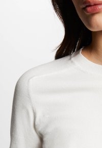 Maglione bianco a maglia con scollo a girocollo, caratterizzato da una consistenza liscia e dettagli a coste sul colletto e sulle spalle.