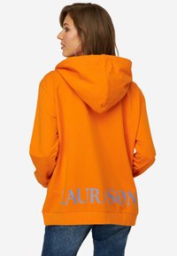 Oranje hoodie met een zachte textuur, voorzien van een capuchon met trekkoord en grote 'LAURASON' print in lichtblauw op de achterkant. Losse pasvorm.