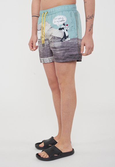Pantaloni da bagno con una stampa grafica blu e grigia che raffigura un personaggio dei cartoni animati. Vita elastica con cordoncino giallo. Realizzati in tessuto leggero.