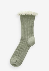 Grüne gerippte Socke mit einem gefransten oberen Rand aus weißer Spitze. Weiche Textur und körpernahe Passform, entworfen für Komfort und Stil.