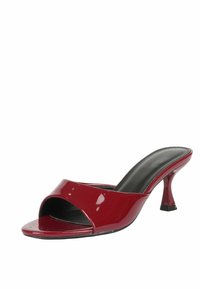 Sandal in pelle lucida rossa con apertura davanti, dotata di una larga fascia incrociata e di un tacco curvo. Fodera interna nera e silhouette elegante.