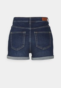 Shorts de mezclilla en azul oscuro con dobladillo enrollado, que cuentan con dos bolsillos traseros y una etiqueta de marca en la cinturilla. Textura suave.