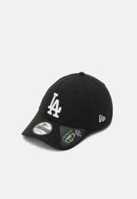 Gorra de béisbol negra con un logo bordado en blanco que dice "LA", correa ajustable y etiquetas que destacan su tejido sostenible. Con corona redondeada y visera.