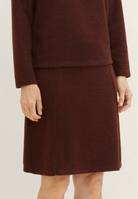 Burgundská pletená svetr s odpovídající sukní; texturovaná látka, volný střih, dlouhé rukávy, boční švy a rovný lem.