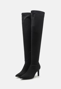 Black over-the-knee boots made of stretchy material, featuring pointed toes and high stiletto heels. Smooth texture with minimal stitching.