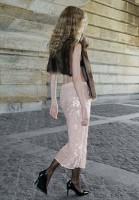 Modèle marchant dans un gilet en fourrure marron, un top noir et une jupe rose à sequins avec des motifs floraux. Elle porte des bas transparents noirs et des chaussures à talons hauts.
