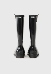 Une paire de bottes de pluie hautes noires Karl Lagerfeld présentées de dos sur un fond blanc.