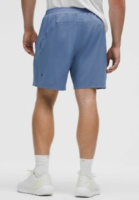 Pantalones cortos deportivos para hombre en tela azul claro, con una banda elástica en la cintura y dos bolsillos laterales. Textura suave, longitud por encima de la rodilla.