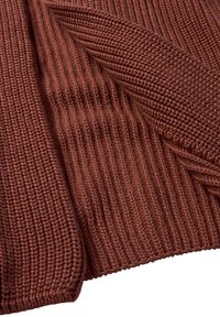 Rustfarbener Strickstoff mit gerippter Textur und diagonalem Muster. Weiche, dicke Garne verleihen ein gemütliches Erscheinungsbild und zeigen ausgeklügelte Stichdetails.