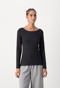 Black long-sleeve t-shirt with a wide neckline, smooth texture, and fitted design. Paired with light gray, loose-fitting trousers.
