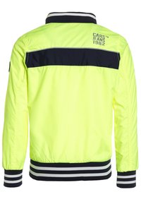 Neon gul bomberjacka med ett marinblått horisontellt streck över ryggen, ribbade muddar och nederkant med svarta och vita ränder.