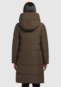 Manteau matelassé marron avec capuche, présentant un quiltage horizontal et une étiquette sur le côté inférieur gauche. Texture douce et mate. Manches longues.
