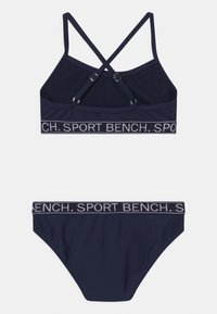 Mornarska bikini setki z racerback zgornjim delom in nastavljivimi naramnicami ter logotipnim pasom, v kompletu z usklajenim spodnjim delom. Gladka tekstura tkanine.