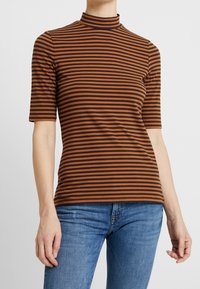 Camisa de rayas con cuello alto, con rayas horizontales en marrón y azul marino. Mangas cortas y un diseño ajustado.