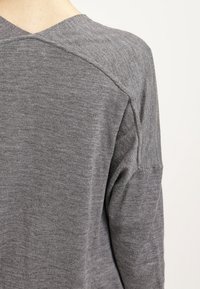 Suéter de punto gris con diseño de cuello en V, que presenta mangas raglán, una textura suave y una silueta ajustada en la parte posterior.
