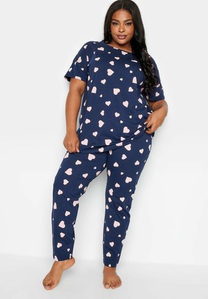 Ensemble de pyjama bleu marine en tissu doux, comprenant un col rond, des manches courtes et des cœurs roses imprimés. Le pantalon est fuselé avec une taille élastique.