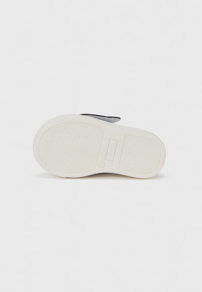 Σόλα παπουτσιού με υφή λευκού καουτσούκ, που διαθέτει μοτίβο πέλματος σε ζιγκ-ζαγκ και γκρι λεπτομέρεια κοντά στη φτέρνα. Απλός και λειτουργικός σχεδιασμός.