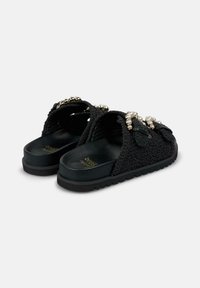 Scarpe nere senza lacci con un design testurizzato, decorate con grandi accenti di perle e una suola morbida e ammortizzata per il massimo comfort.