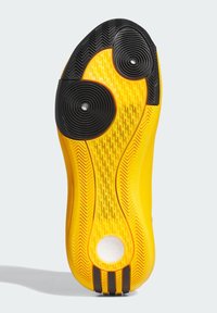 Gele sport schoenen uitloop met een gestructureerd oppervlak, zwarte ronde traction pads en een witte ronde detail bij de hiel.