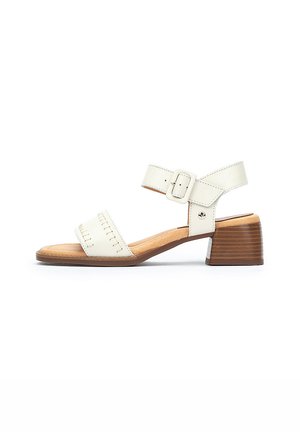 Sandale en cuir blanc avec un talon en bois bas, une sangle de cheville et une boucle, présentant des détails cousus sur la zone des orteils et une semelle intérieure lisse.