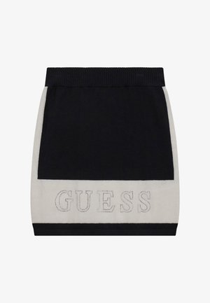 Mini-jupe noire et blanche avec taille côtelée et logo « GUESS » souligné de clous près de l'ourlet.