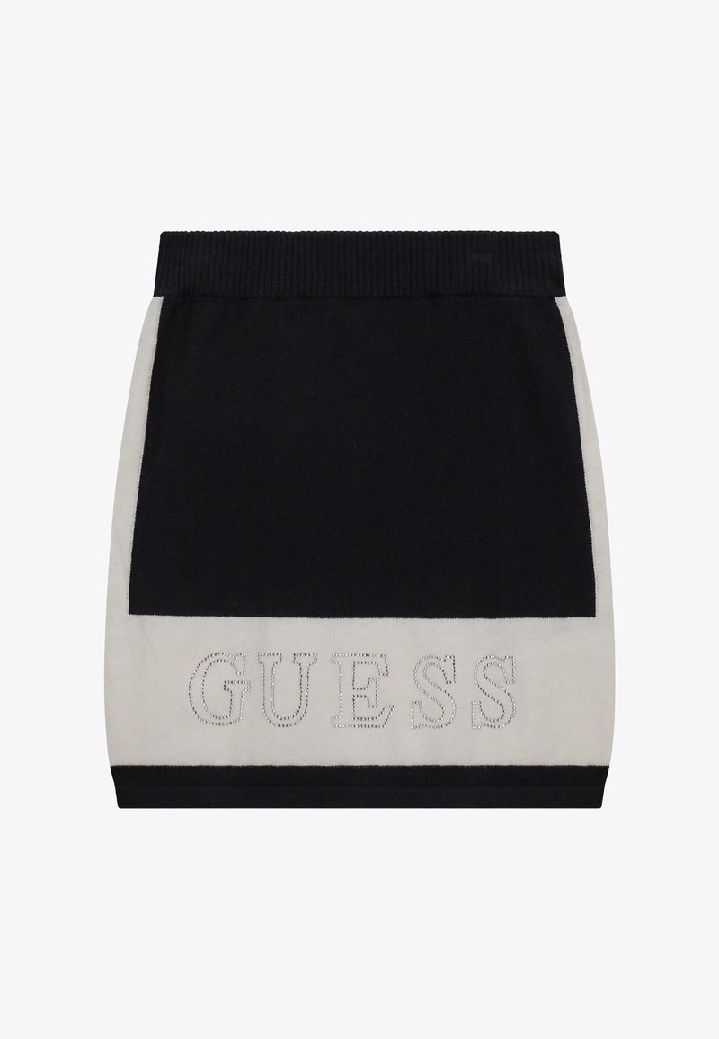 Mini-jupe noire et blanche avec taille côtelée et logo « GUESS » souligné de clous près de l'ourlet.