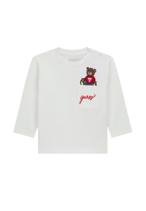 Chemise blanche à manches longues en coton biologique, avec un ours brodé portant une chemise rouge sur la poche poitrine et le texte "guess" en rouge.