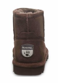 Botte de cheville en suede marron avec une doublure intérieure douce, une forme arrondie et un patch logo Bearpaw distinctif sur le talon.