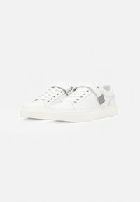 Weiße Ledersneaker mit rundlicher Zehenpartie, strukturierter Oberseite, flachen Schnürsenkeln und einem Riemen mit metallischem Akzent; Gummisohle mit minimalem Profil.