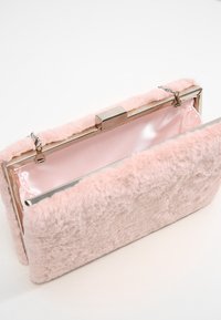 Blush pink clutch made of soft faux fur with a shiny metallic frame. Interior features a smooth satin lining and a clasp closure.