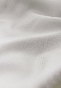 White fabric with a subtle geometric pattern, showcasing a smooth texture and a light, airy appearance.