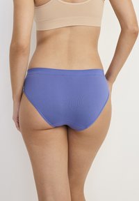 Niebieskie bawełniane majtki slipki o gładkim wykończeniu i elastycznym pasku, pokazane z tyłu, podkreślające ich kształt i dopasowanie.