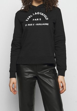 Schwarzer Pullover mit rundem Halsausschnitt, langen Ärmeln und geripptem Saum, mit weißem Text, der "Karl Lagerfeld Paris 21 Rue St-Guillaume" lautet.