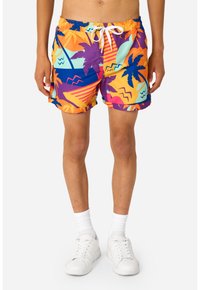 Farverige badeshorts med et mønster af palmer, geometriske former og bølgede linjer i lilla, orange og blågrøn med snøre i taljen.