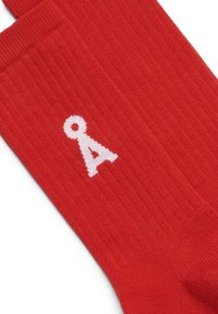 Rode geribbelde sokken met een witte gebreide afbeelding van de letter "A" op de zijkant. Het materiaal lijkt zacht met een gestructureerde afwerking.