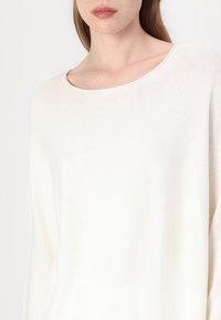 Biały sweter dziany z szerokim dekoltem i długimi rękawami, z delikatnym teksturowanym wzorem i miękką, lekką tkaniną.