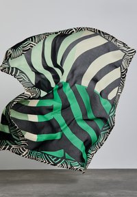 Grøn- og sortmønstret tørklæde med kraftige zigzag- og stribedesign. Letvægts, flydende stof med en kontrasterende geometrisk kant.