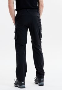 Svarta cargobyxor tillverkade av lättviktsmaterial har dragkedje- och lockfickor, tapered design och manschetter med justerbara stängningar.