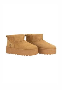 Botas de tobillo de ante en color marrón claro con una suela plana y gruesa, que presentan una punta redondeada y un diseño minimalista. En la parte trasera incluyen una pequeña cinta para facilitar el calzado.