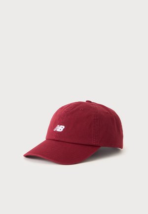 Casquette de baseball New Balance marron avec visière incurvée et logo blanc brodé à l'avant, présentée sur un fond clair uni.