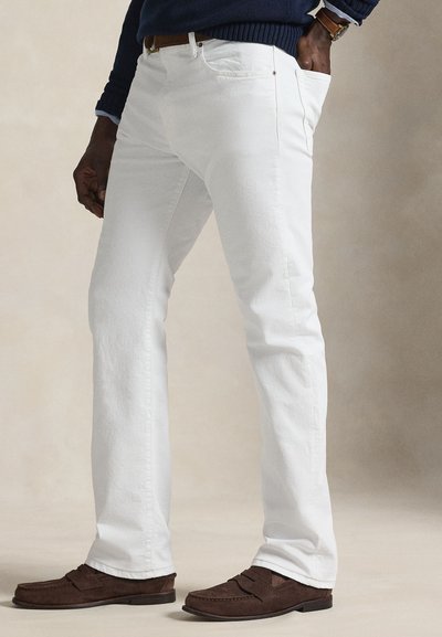 Λευκά τζιν παντελόνια με ίσια γραμμή. Διαθέτουν μπροστινές τσέπες και διακριτικές ραφές. Φορεμένα με καφέ μοκασίνια από σουέντ.