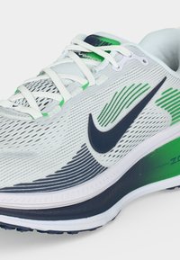 Λευκό και πράσινο αθλητικό παπούτσι Nike με μαύρο λογότυπο swoosh, άσπρα κορδόνια και επενδεδυμένη σόλα με τη σήμανση "Zoom" στη φτέρνα.