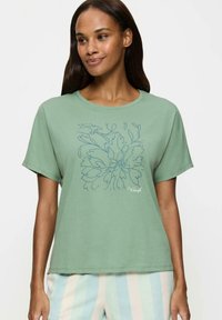 Zielona bawełniana koszulka z krótkim rękawem, z okrągłym dekoltem i luźnym fasonem, z przodu z rysunkiem kwiatowym w niebieskim kolorze.