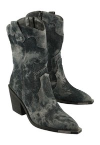 Botas de vaquero de mezclilla en gris con un acabado texturizado, puntera afilada y tacón bajo cuadrado. Presentan costuras decorativas y acentos metálicos.