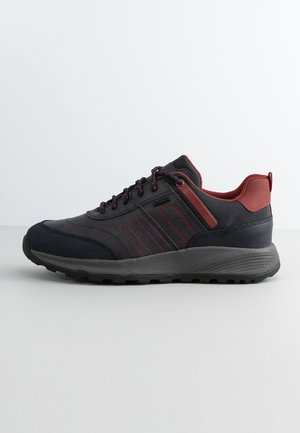 Black and dark red athletic shoe with a textured upper, thick black sole, reinforced toe, and contrasting red accents on the sides.